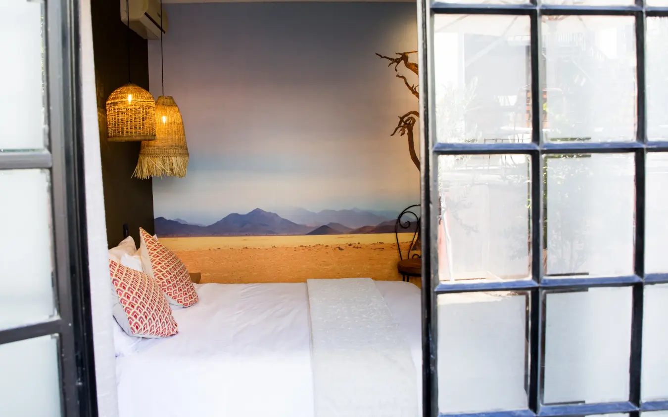Bedroom interior with desert landscape mural and woven pendant lights, Olive Grove Guesthouse, Windhoek, Namibia