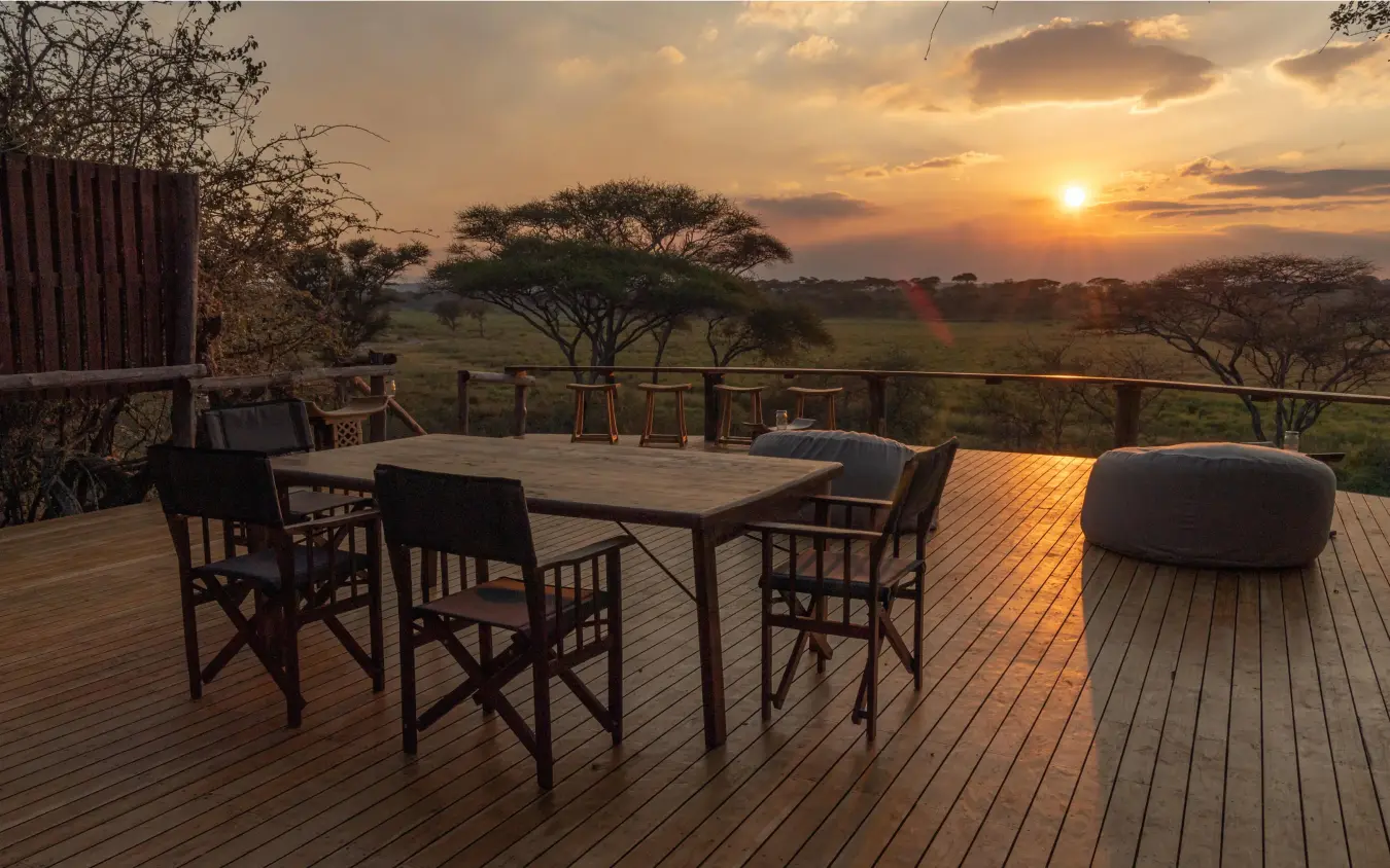 Wooden deck overlooking savanna at sunset with acacia trees, Oliver’s Camp, Tarangire National Park, Tanzania