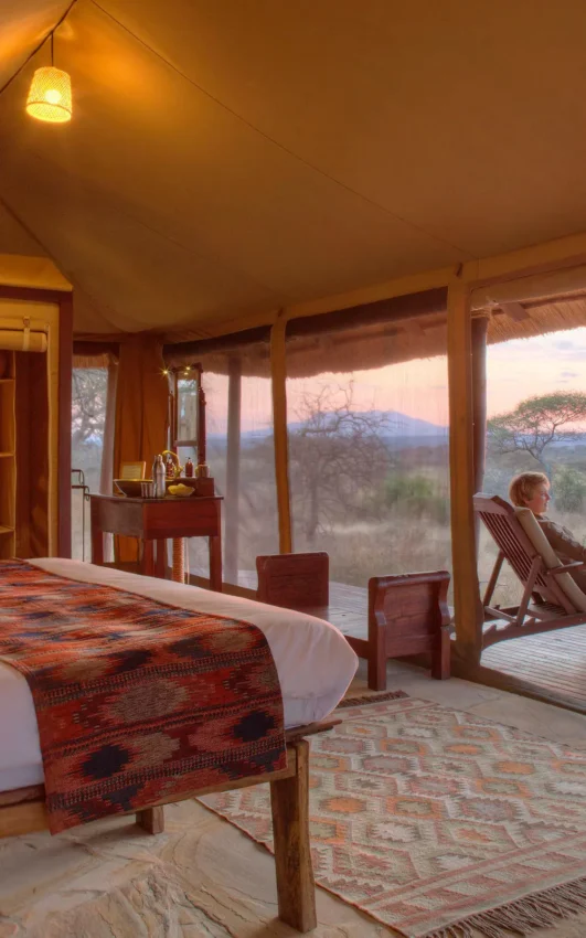Bedroom with expansive windows overlooking African savanna sunset, Oliver’s Camp, Tarangire National Park, Tanzania