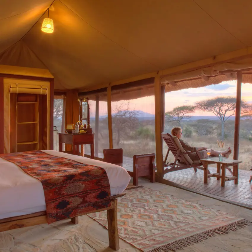Bedroom with expansive windows overlooking African savanna sunset, Oliver’s Camp, Tarangire National Park, Tanzania
