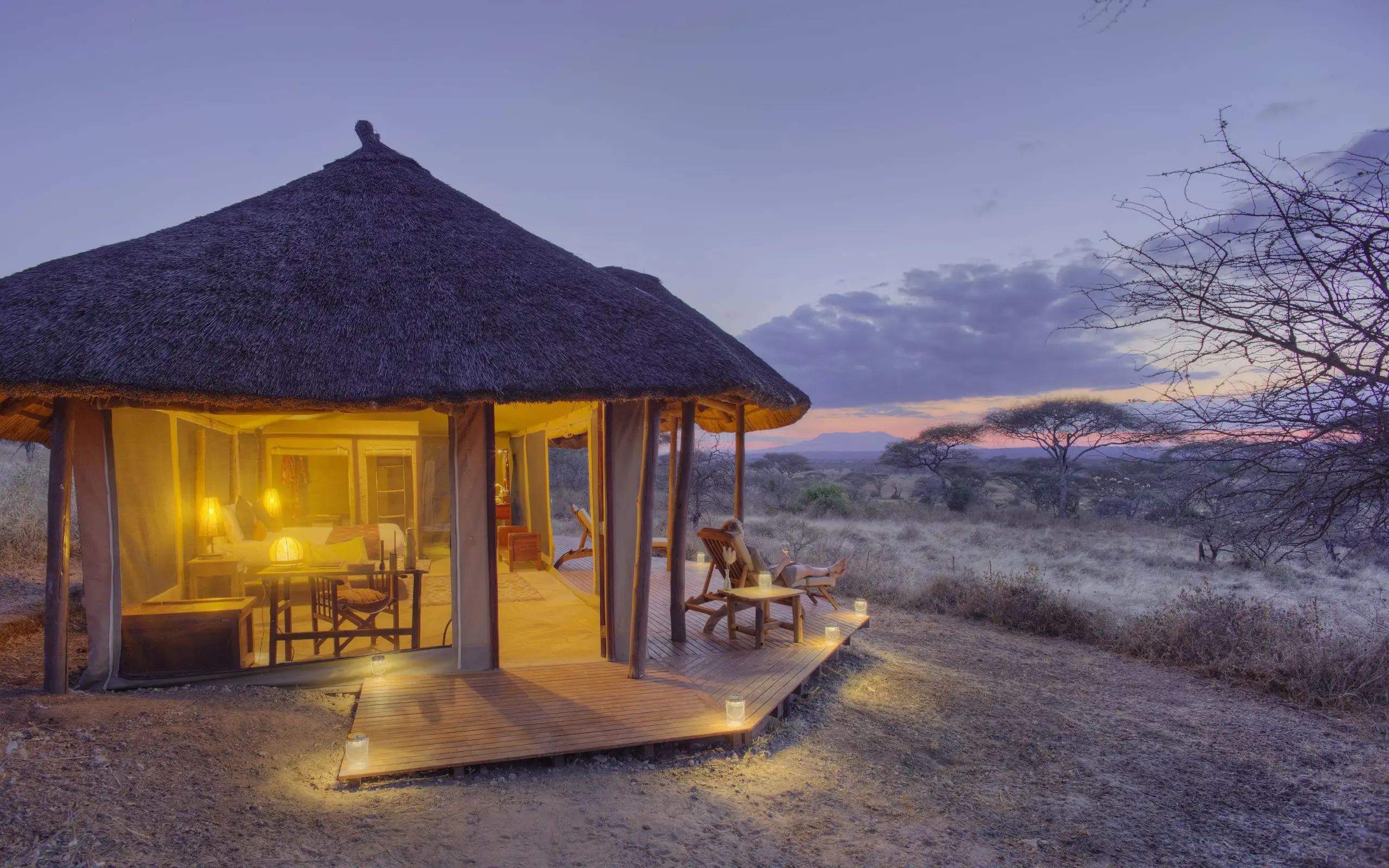 Thatched safari lodge at dusk with savanna landscape, Oliver’s Camp, Tarangire National Park, Tanzania