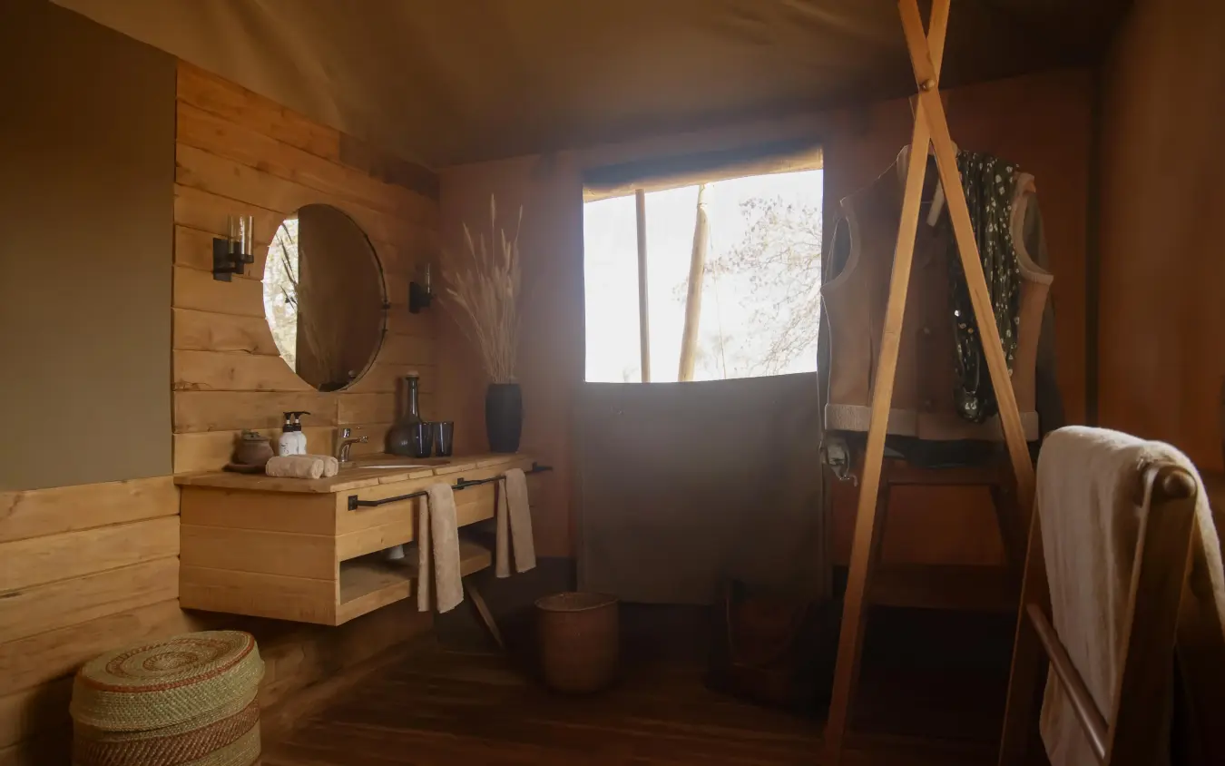 Wooden bathroom interior with round mirror and window overlooking natural landscape, Olkeri Camp, Tarangire National Park, Tanzania