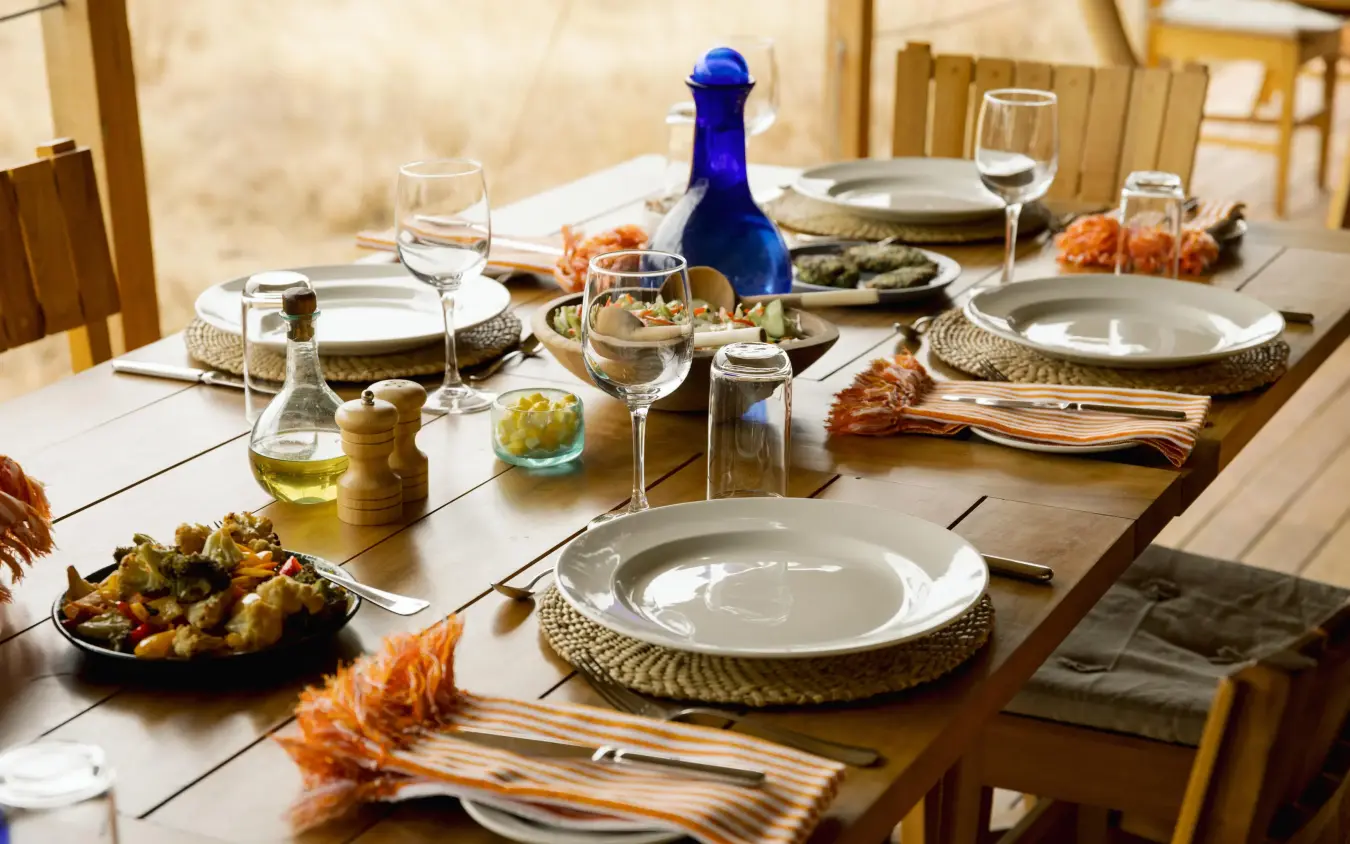 Elegant outdoor dining table set with white plates and blue wine bottle, Olkeri Camp, Tarangire National Park, Tanzania