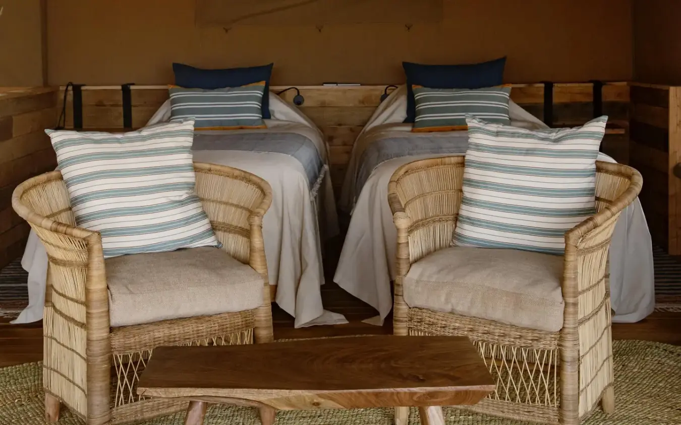 Twin beds with striped cushions and wicker chairs in safari lodge bedroom, Olkeri Camp, Tarangire National Park, Tanzania