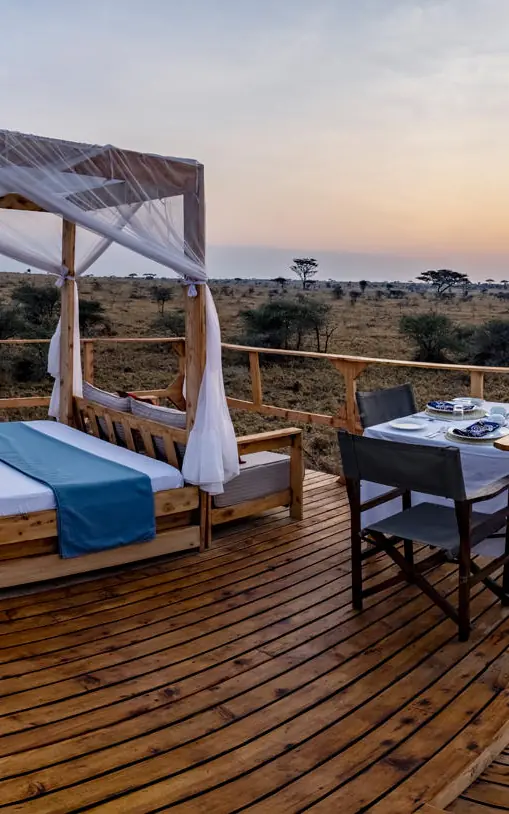 Four-poster bed on wooden deck at sunset, Olmara Serengeti, Serengeti National Park, Tanzania