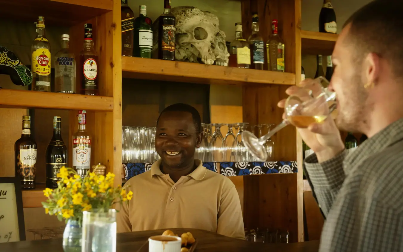 Two men enjoying drinks at a wooden bar with skull decor, Olmara Serengeti, Serengeti National Park, Tanzania