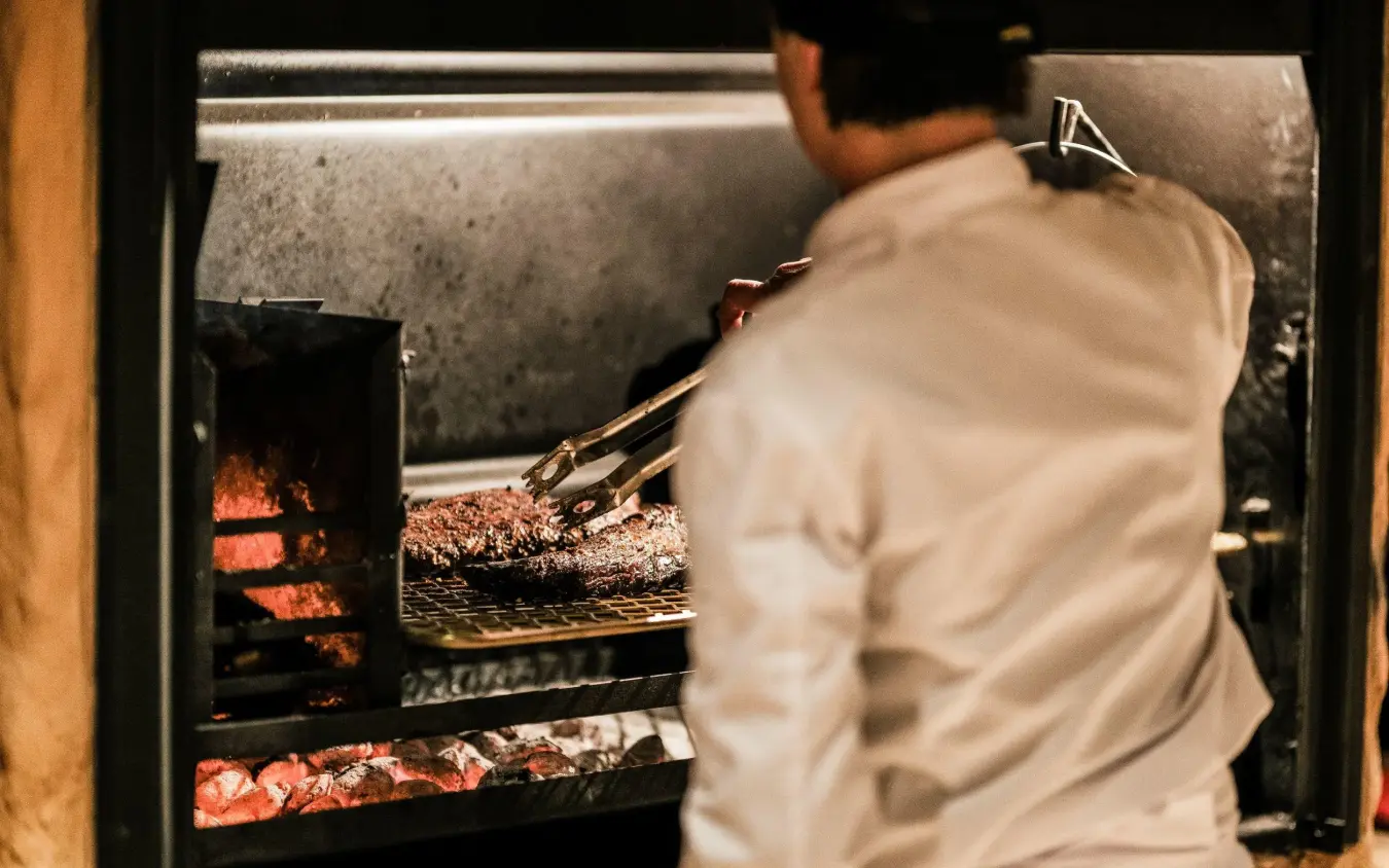 Chef preparing meat on open flame grill, Omaanda, Windhoek, Namibia