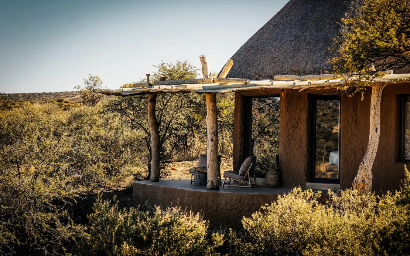 Thatch-roofed lodge with wooden deck overlooking savanna, Omaanda, Windhoek, Namibia