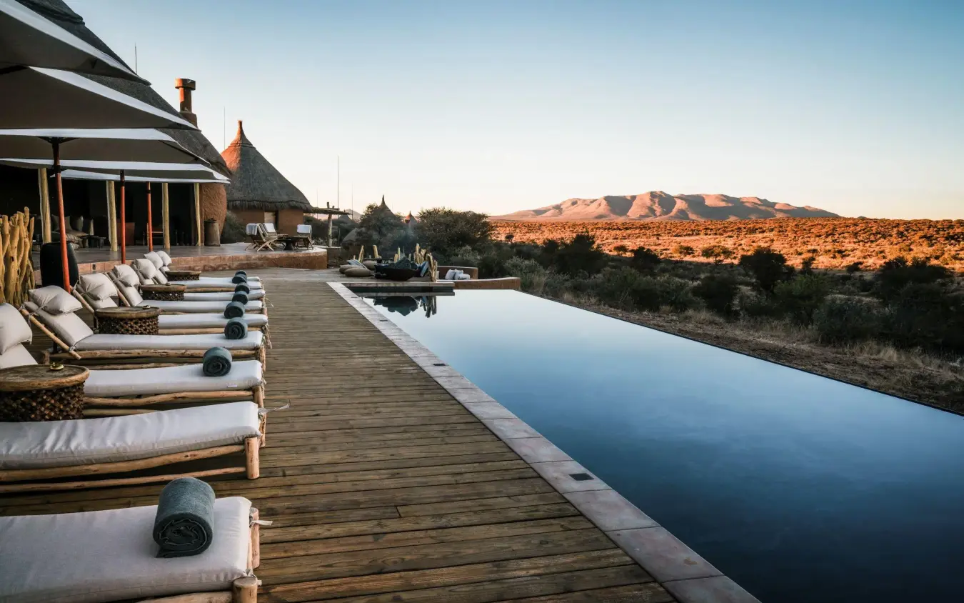 Infinity pool with loungers overlooking desert landscape, Omaanda, Windhoek, Namibia