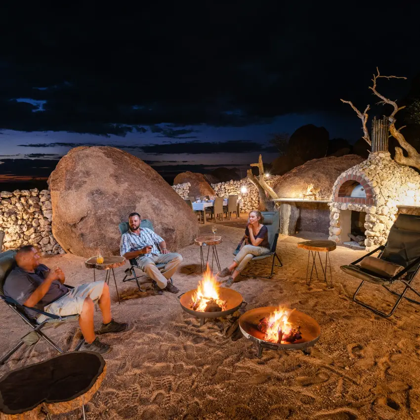 Guests gathered around fire pits at twilight under stars, Onduli Ridge, Damaraland, Namibia