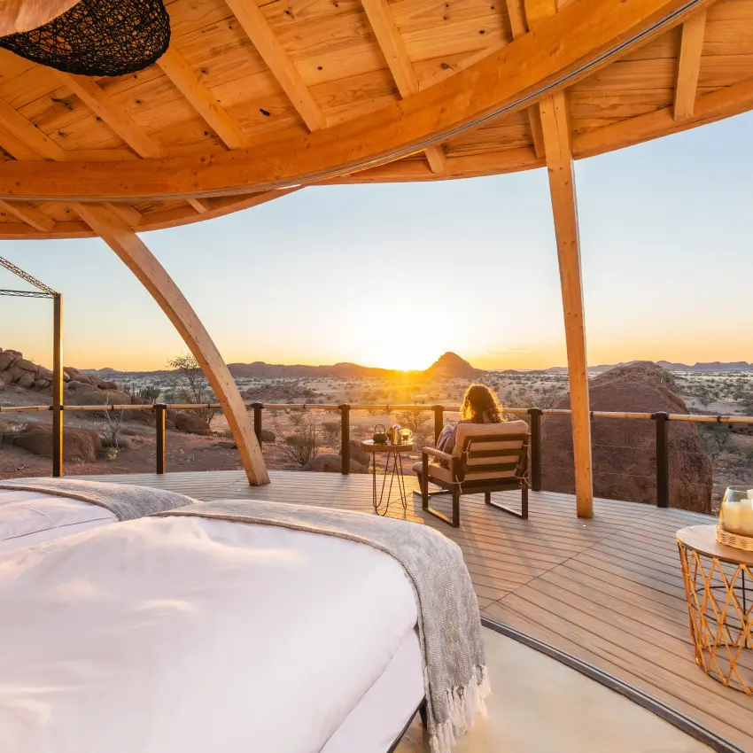 Wooden deck bedroom overlooking desert landscape at sunset, Onduli Ridge, Damaraland, Namibia