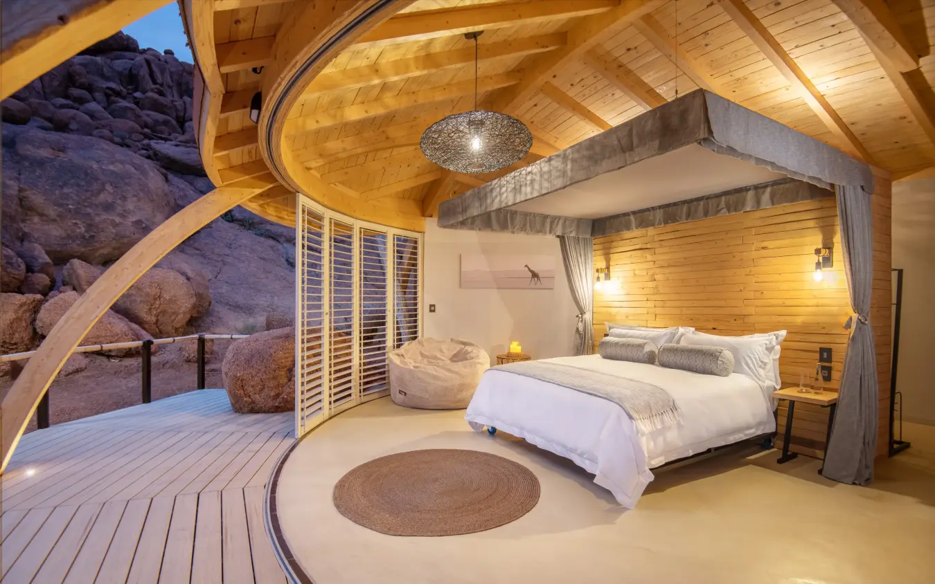 Luxury bedroom with canopy bed and desert rock views, Namibia