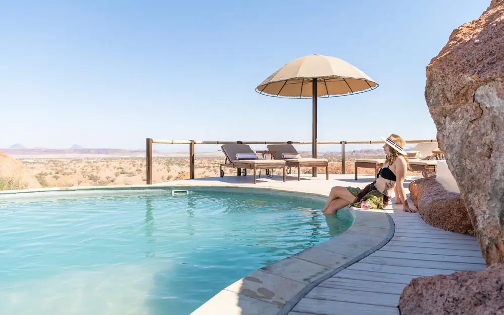 Swimming pool with umbrella overlooking arid landscape, Onduli Ridge, Damaraland, Namibia
