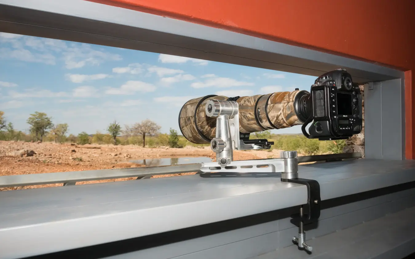 Professional camera mounted on safari vehicle roof rail overlooking bushland, Ongava Lodge, Etosha National Park, Namibia