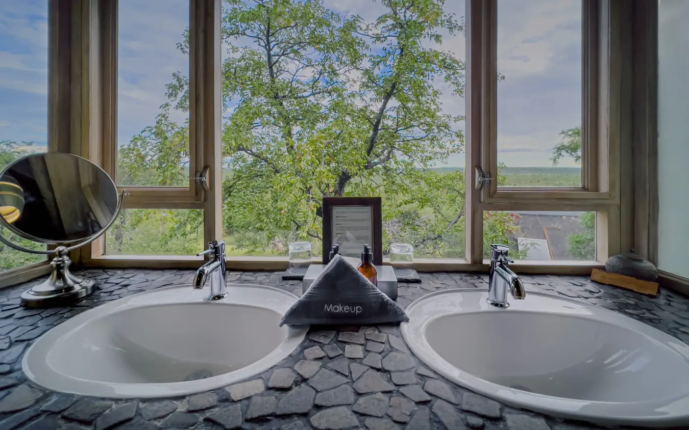 Luxury bathroom with dual sinks overlooking tree-filled landscape, Ongava Lodge, Etosha National Park, Namibia