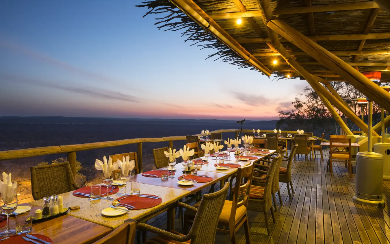 Outdoor dining deck with table setting overlooking savanna at dusk, Ongava Lodge, Etosha National Park, Namibia