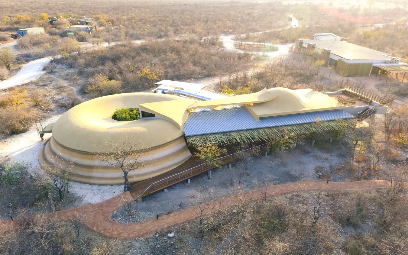 Modern curved building with green roof overlooking river and woodland landscape, Ongava Lodge, Etosha National Park, Namibia
