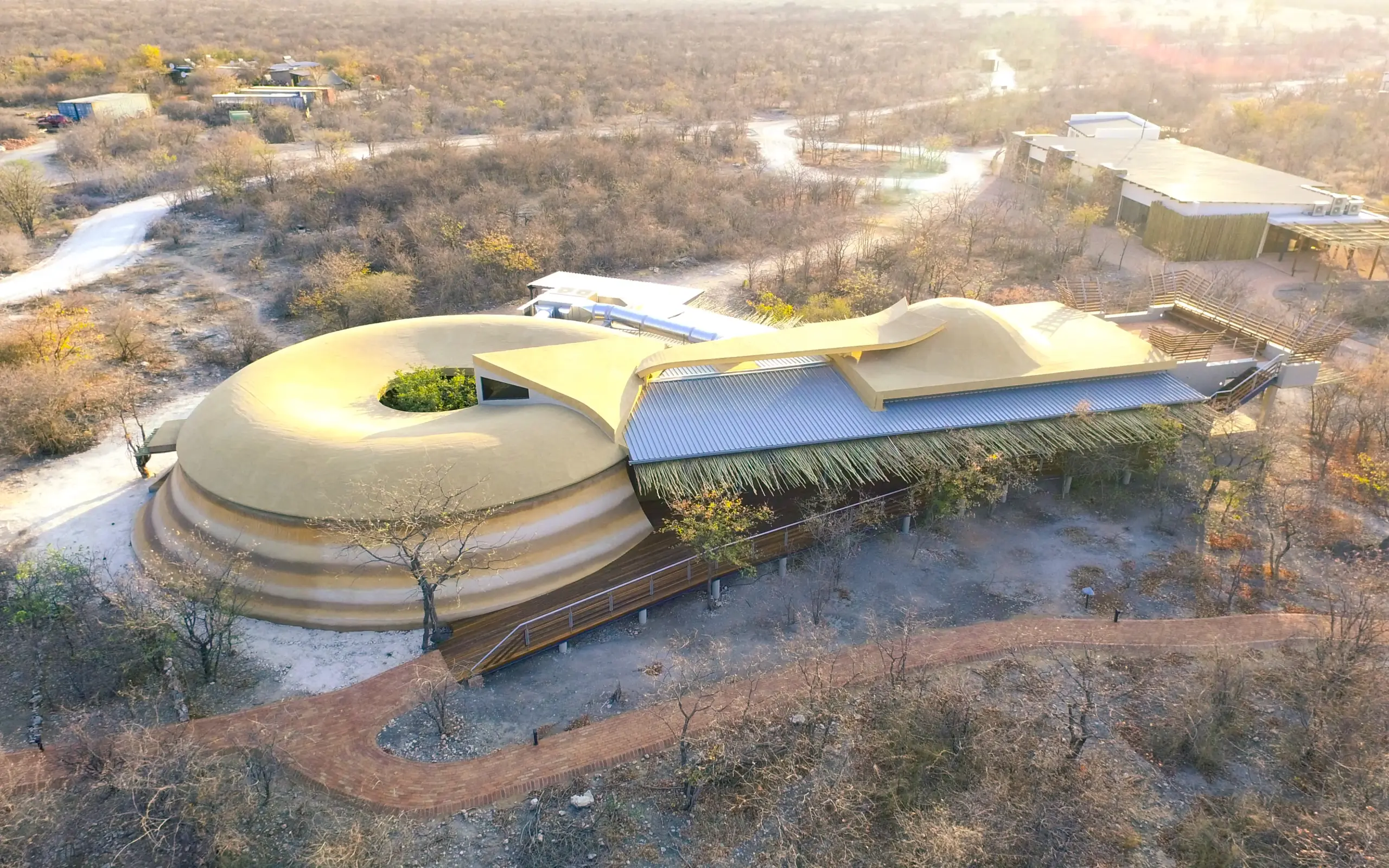 Modern curved building with green roof overlooking river and woodland landscape, Ongava Lodge, Etosha National Park, Namibia