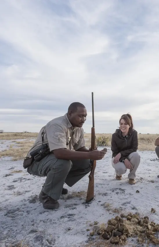 Guide demonstrating wildlife tracking technique in wetland habitat, Onguma Camp Kala, Etosha National Park, Namibia