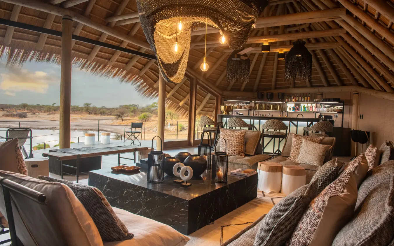 Luxury safari lodge lounge with waterhole view and thatched ceiling, Onguma Camp Kala, Etosha National Park, Namibia
