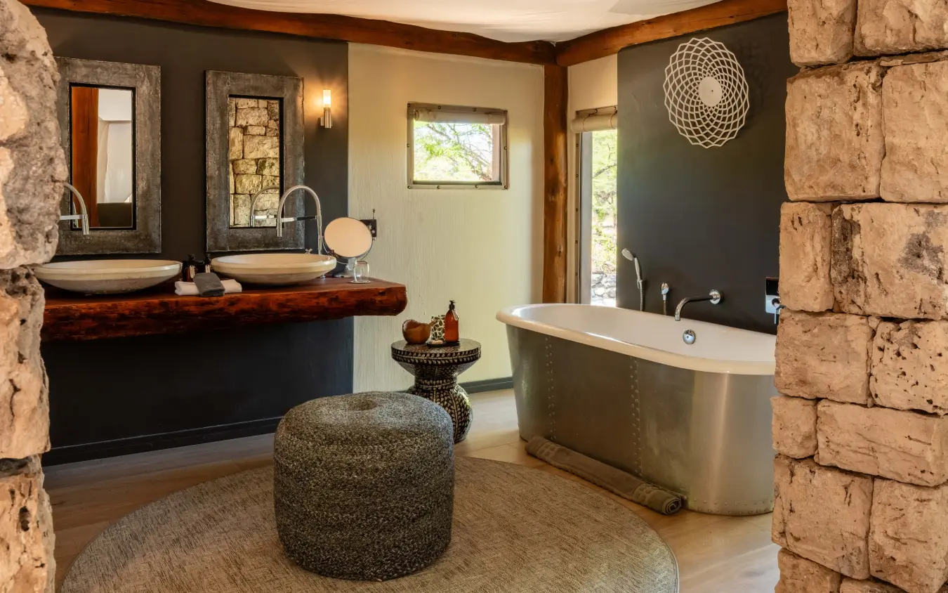 Luxury bathroom with stone walls, dual vanities and freestanding metal bathtub, Onguma Tented Camp, Etosha National Park, Namibia