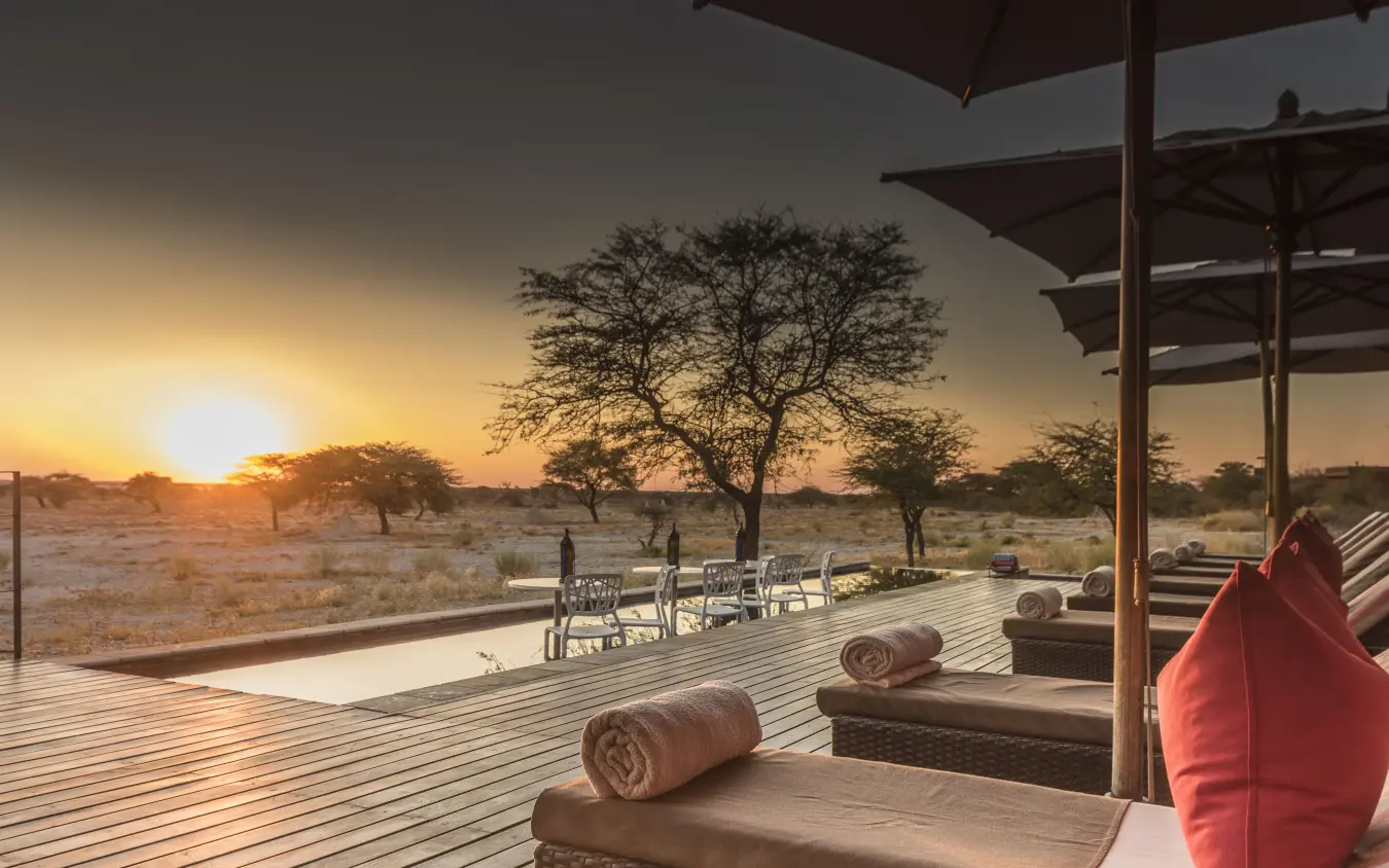 Wooden deck with loungers overlooking savanna landscape at sunset, Onguma Tented Camp, Etosha National Park, Namibia