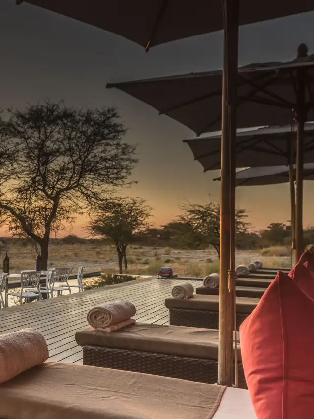 Wooden deck with loungers overlooking savanna landscape at sunset, Onguma Tented Camp, Etosha National Park, Namibia