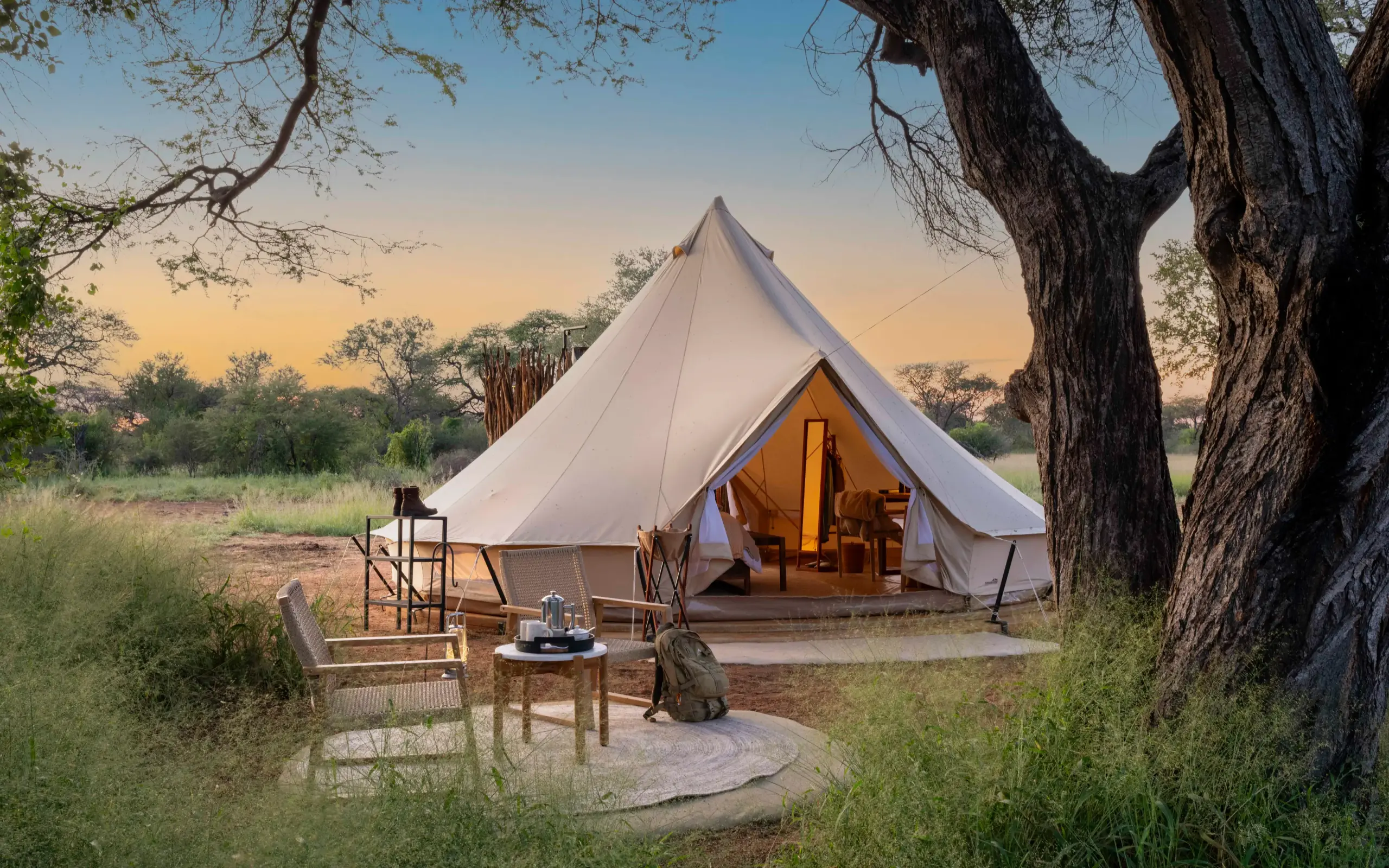 Luxury bell tent camp with seating area under acacia trees at dusk, Onguma Trails Camp, Etosha National Park, Namibia