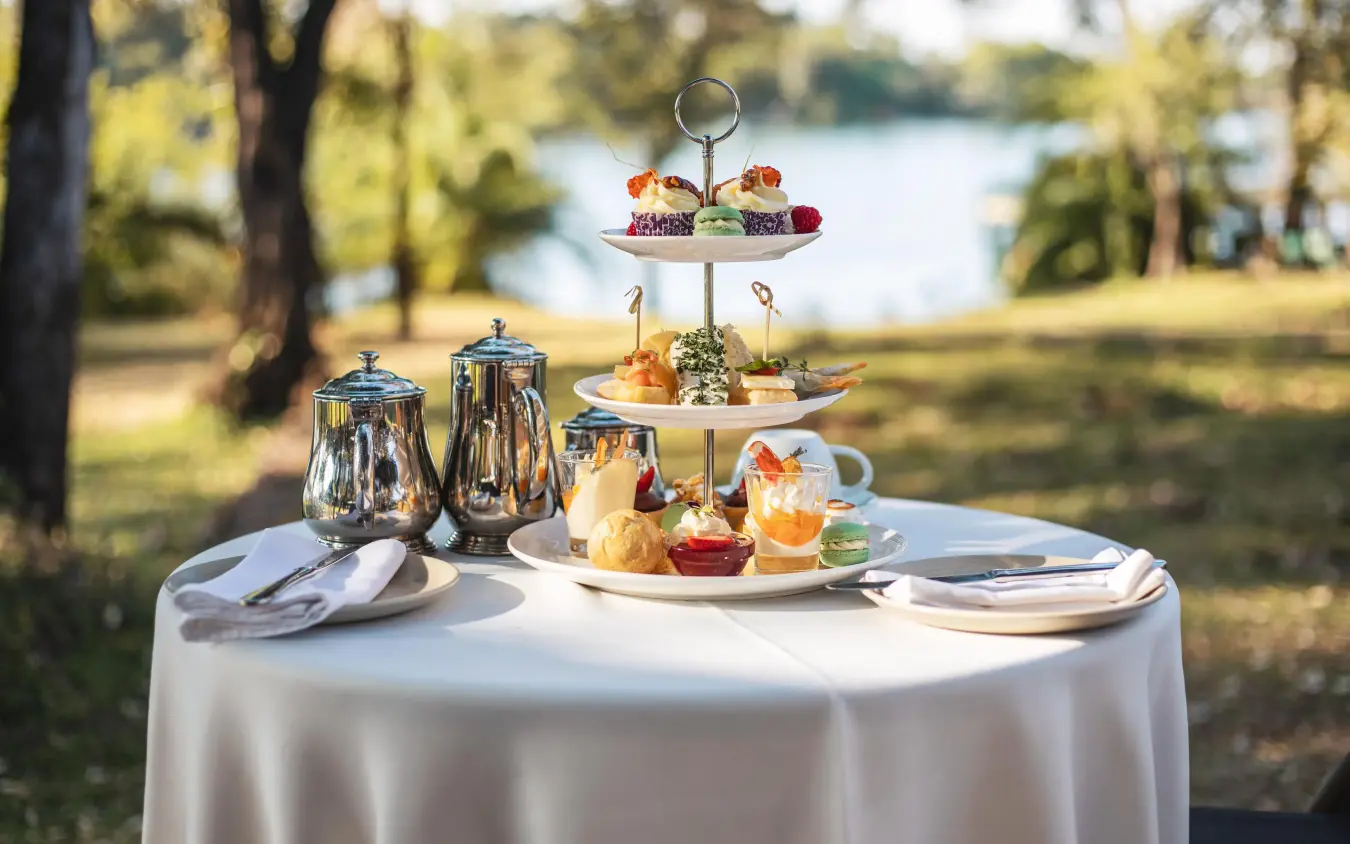 Tiered afternoon tea service on lakeside table setting, Palm River Hotel, Victoria Falls, Zimbabwe