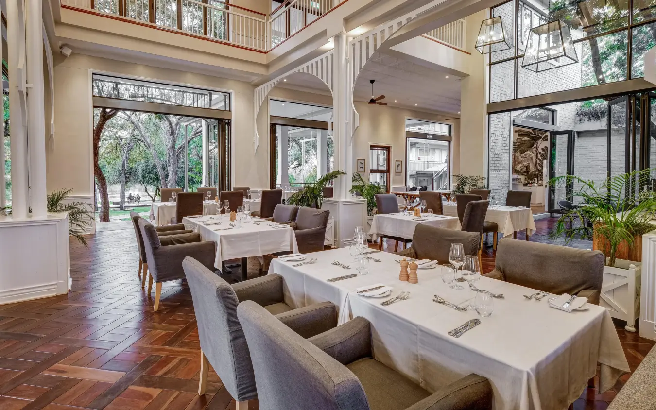 Fine dining restaurant with white tablecloths and large windows, Palm River Hotel, Victoria Falls, Zimbabwe