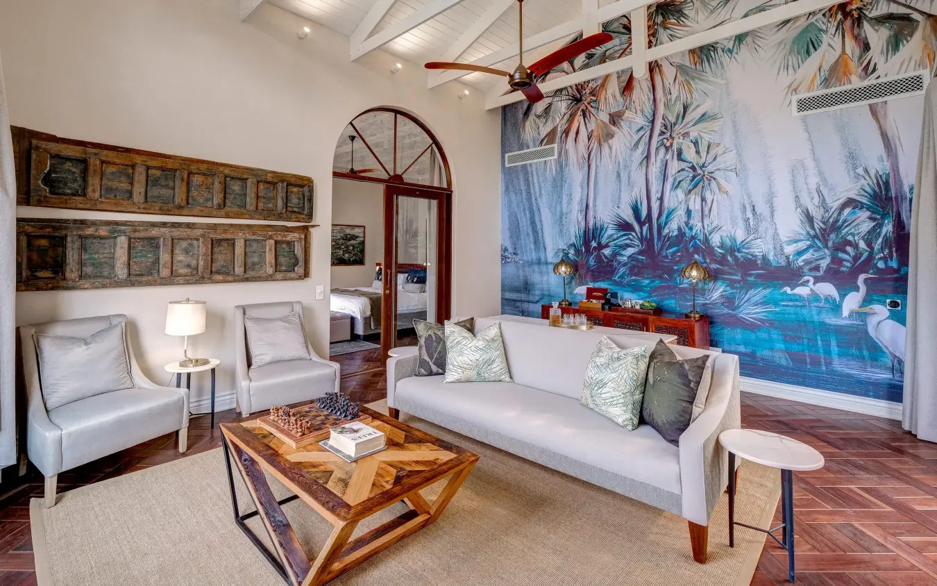 Spacious lounge with white seating and tropical mural artwork, Palm River Hotel, Victoria Falls, Zimbabwe