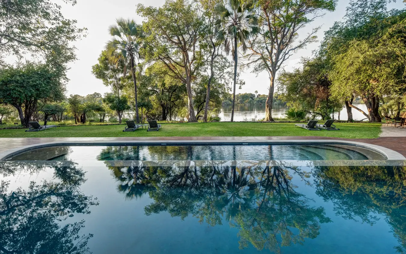 Reflecting pool with tall trees and manicured grounds, Palm River Hotel, Victoria Falls, Zimbabwe