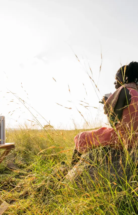 Person sitting in tall grass during safari excursion, Papa’s Camp, Murchison Falls NP, Uganda