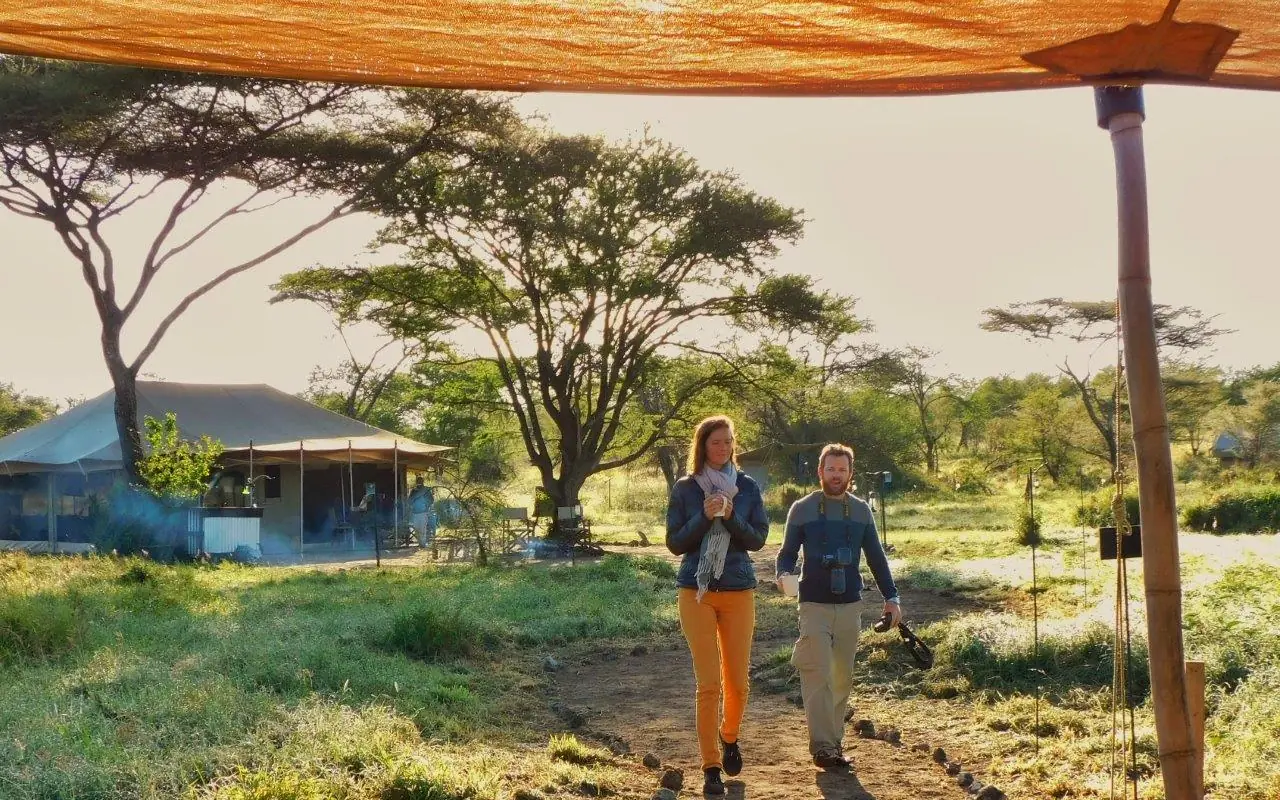 Two guests jogging on dirt path near camp, Pembazoni Camp, Serengeti National Park, Tanzania