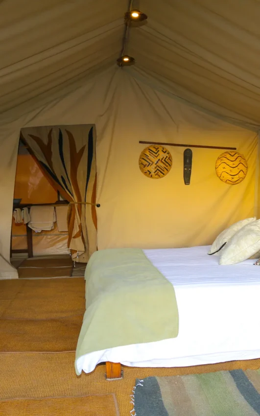 Safari tent bedroom with wooden furniture and canvas walls, Pembazoni Camp, Serengeti National Park, Tanzania