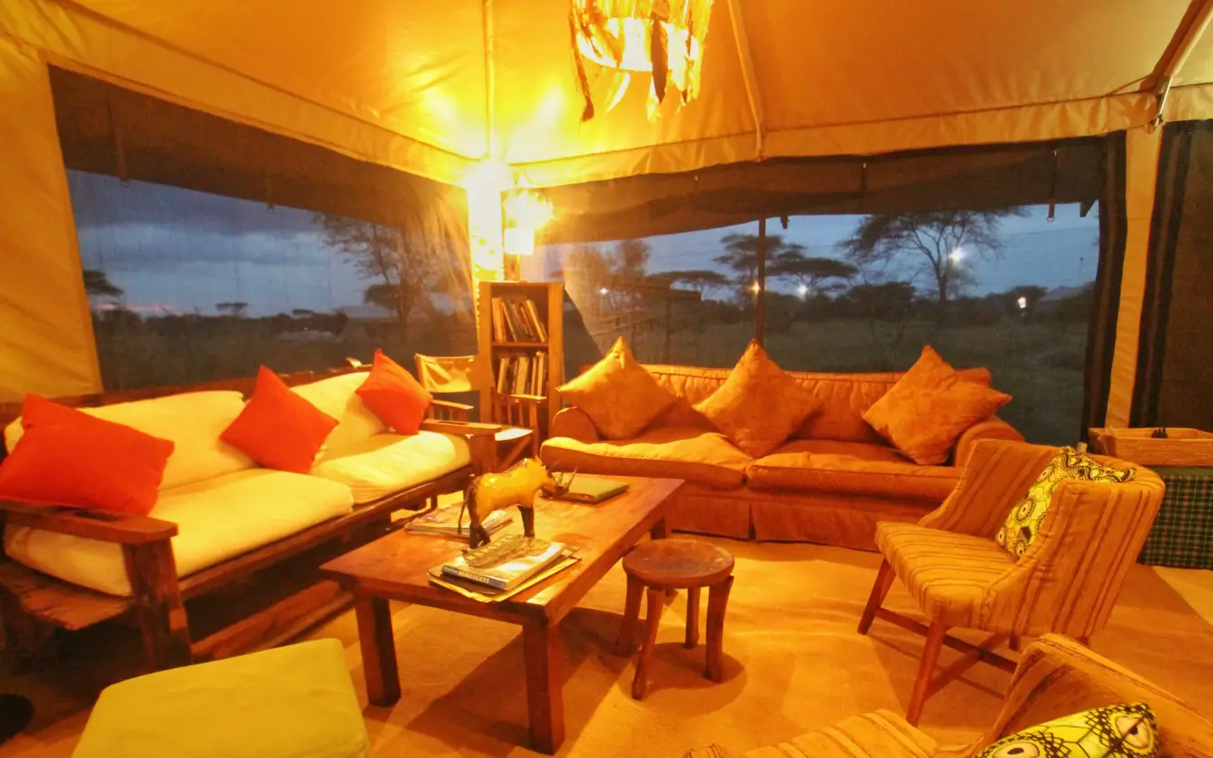 Canvas tent lounge with cushioned seating and savanna views, Pembazoni Camp, Serengeti National Park, Tanzania