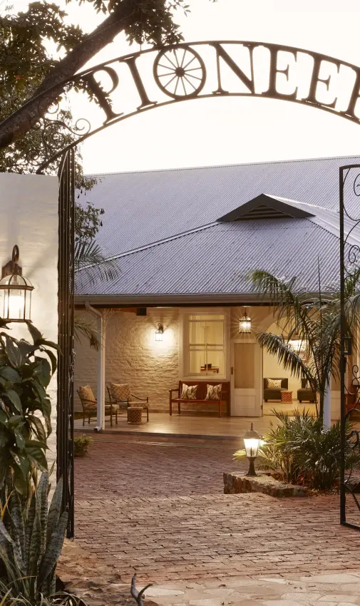 Illuminated entrance courtyard with decorative iron gate at dusk, Pioneers Lodge, Victoria Falls, Zimbabwe