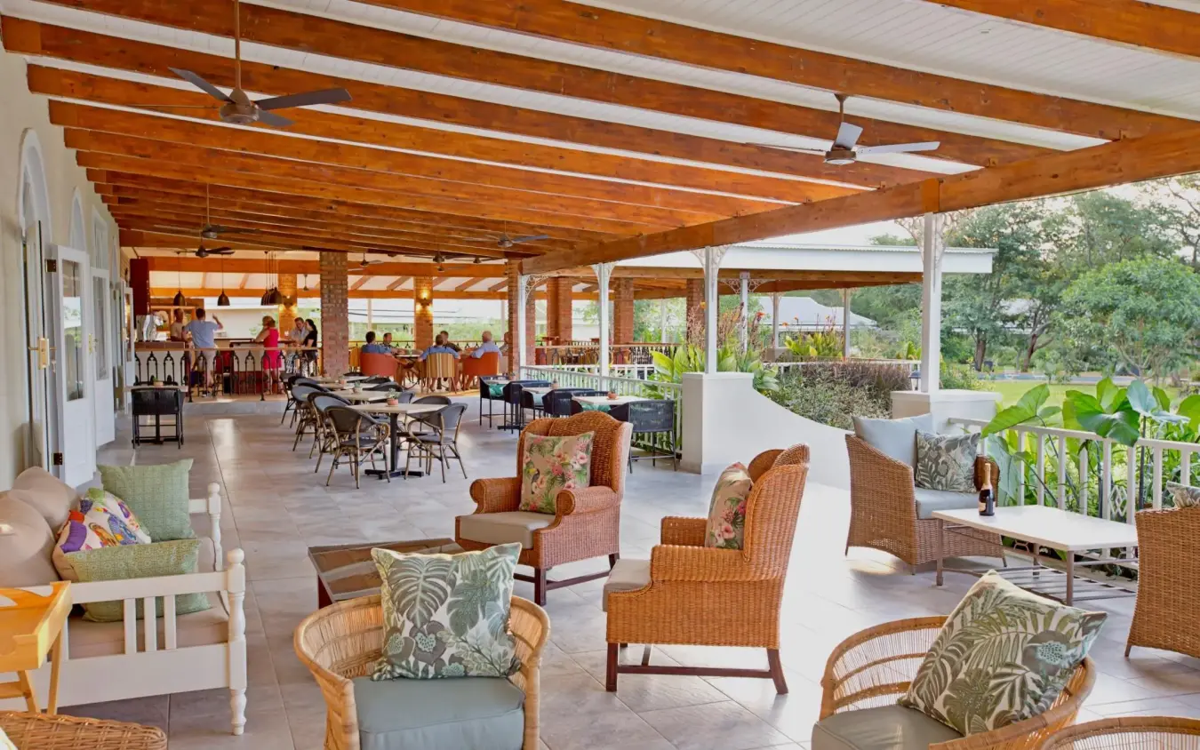 Covered lounge area with wicker furniture and wooden beams, Pioneers Lodge, Victoria Falls, Zimbabwe