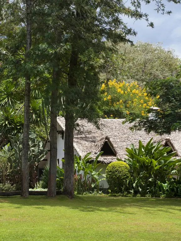 Colonial stone building with manicured lawn and mature trees, Plantation Lodge, Ngorongoro Crater, Tanzania