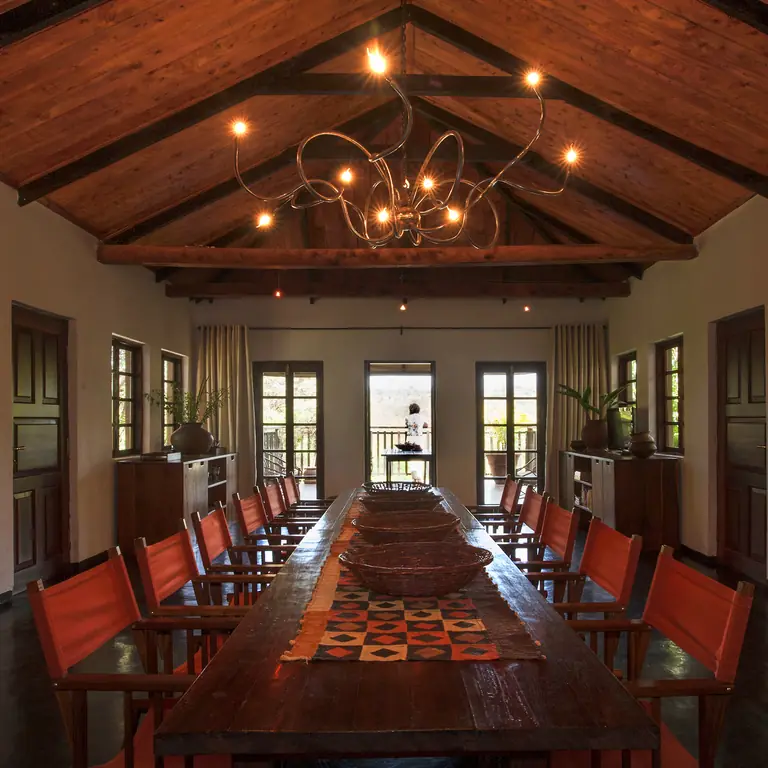 Long wooden dining table with red chairs and wooden beams, Plantation Lodge, Ngorongoro Crater, Tanzania