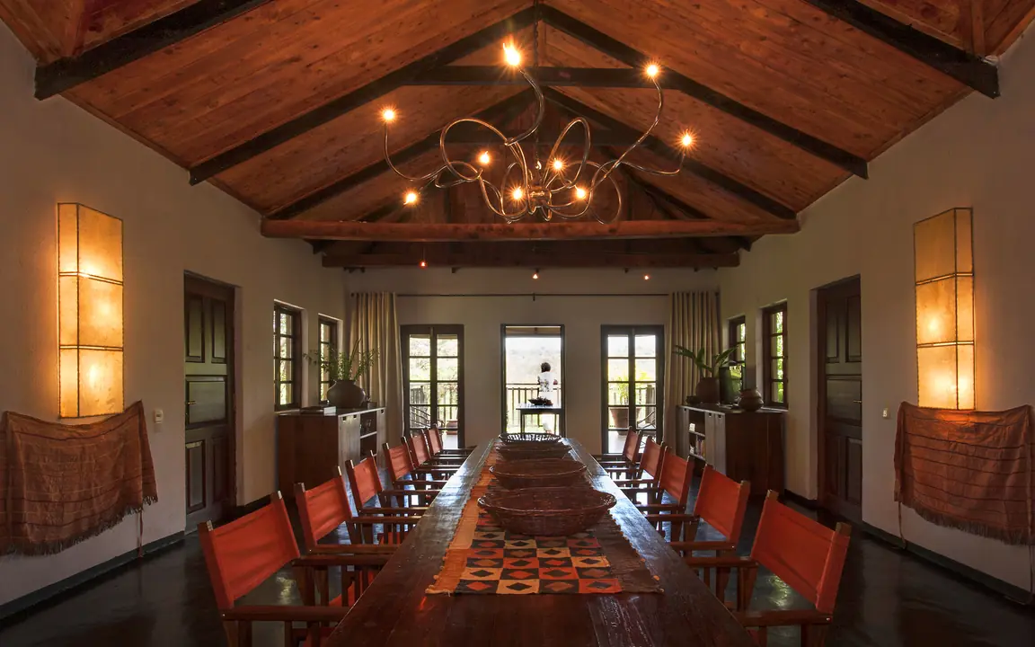 Long wooden dining table with red chairs and wooden beams, Plantation Lodge, Ngorongoro Crater, Tanzania
