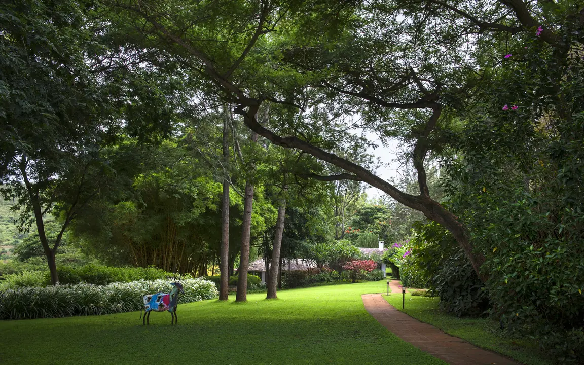 Tree-lined garden path with manicured lawn and visitors, Plantation Lodge, Ngorongoro Crater, Tanzania