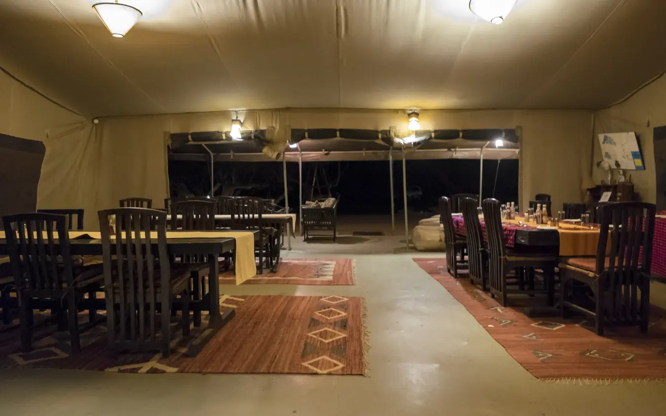 Safari dining tent with tables set for evening service under canvas roof, Porini Amboseli Camp, Amboseli and Chyulu Hills, Kenya