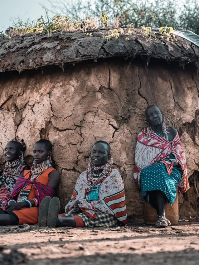 Maasai women and children sitting outside traditional mud-thatched dwelling, Porini Amboseli Camp, Amboseli and Chyulu Hills, Kenya