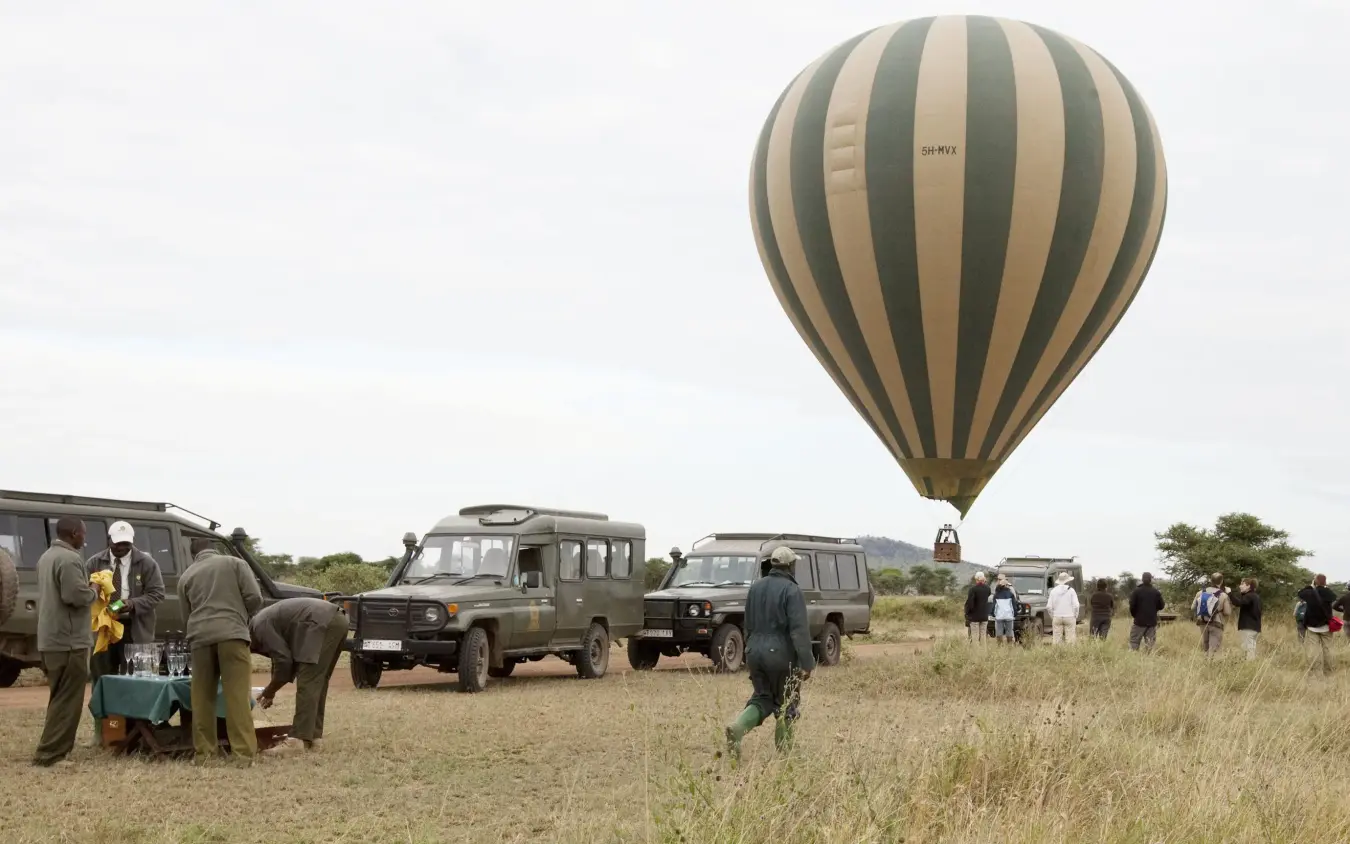 Hot air balloon landing with safari vehicles and guests, Rekero Camp, Maasai Mara, Kenya