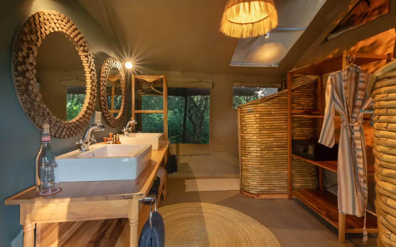 Luxury bathroom with circular mirrors and wooden vanity, Rekero Camp, Maasai Mara, Kenya