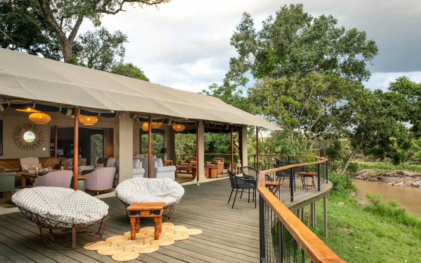 Safari lodge deck with river view and acacia trees, Rekero Camp, Maasai Mara, Kenya