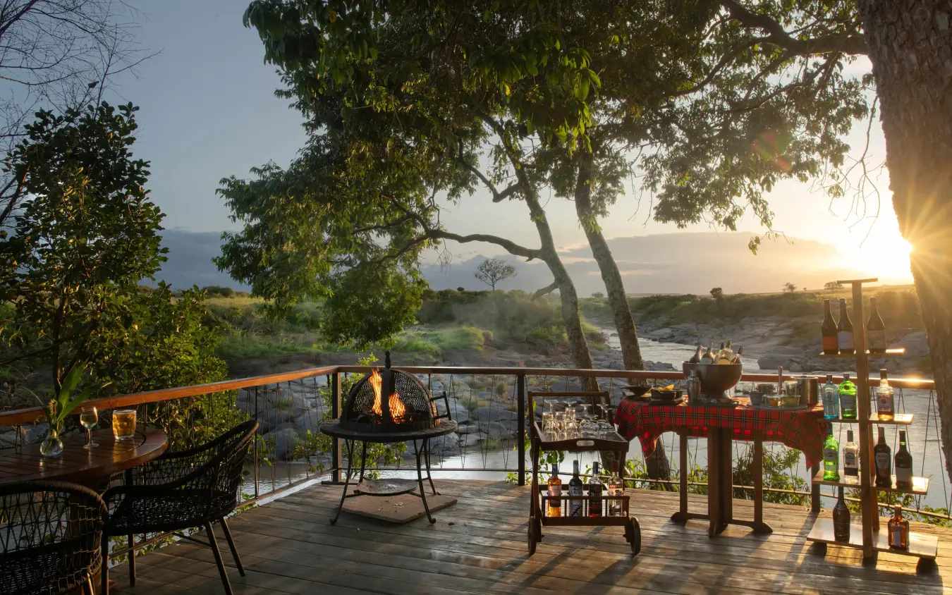 Wooden deck overlooking river at sunset with trees, Rekero Camp, Maasai Mara, Kenya
