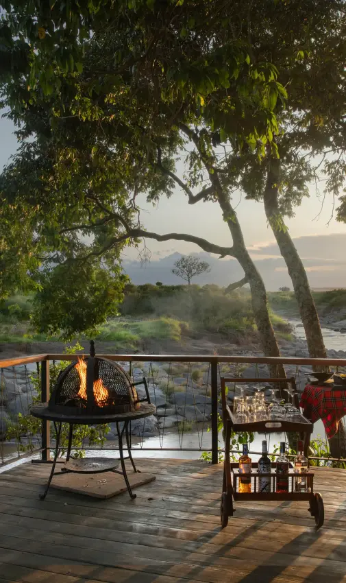 Wooden deck overlooking river at sunset with trees, Rekero Camp, Maasai Mara, Kenya