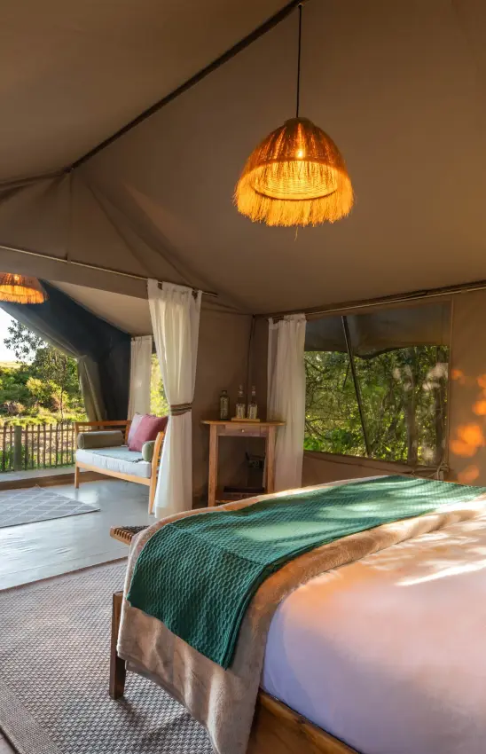Luxury safari tent bedroom with views of woodland landscape, Rekero Camp, Maasai Mara, Kenya